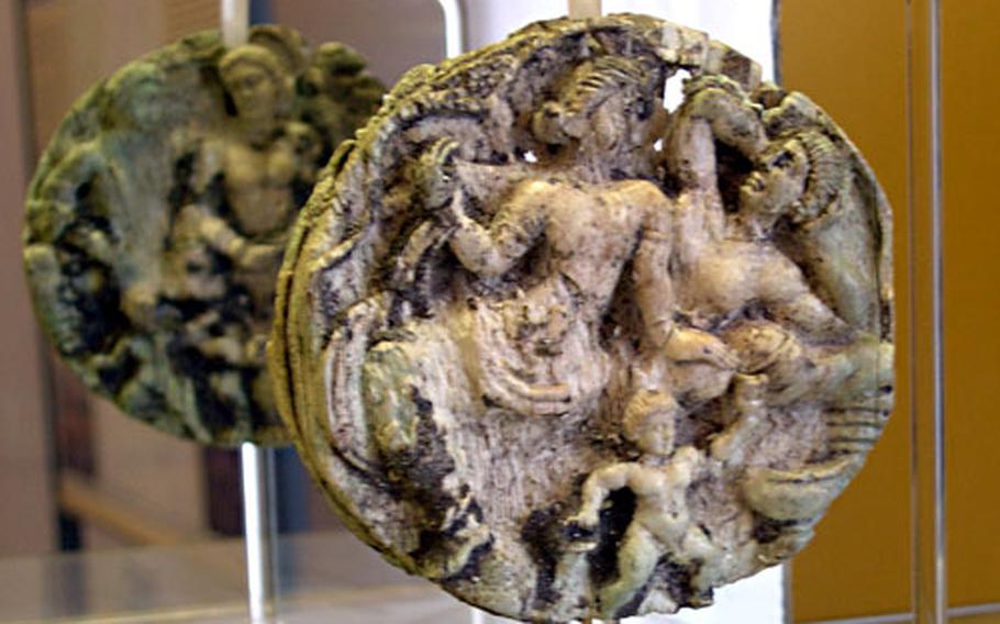 The back side of this ornamental disk is reflected in a mirror. The disk is one of the few hundred items at the Museo Archeologico dell'Agro Atellano in Succivo, north of Naples.
