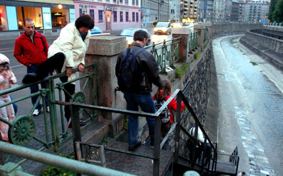 Tour-goers climb a railing to reach the entrance to the underground alongside Vienna’s Wien River. After a half-mile, the river disappears into the city’s main tunnel.