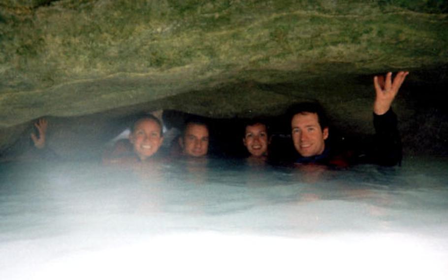 Canyoners — water up to their chins, a rock ledge above their heads — take a break for a group photo before moving on down the Vero River canyon in Spain's Parque de la Sierra y los Cañones de Guara.