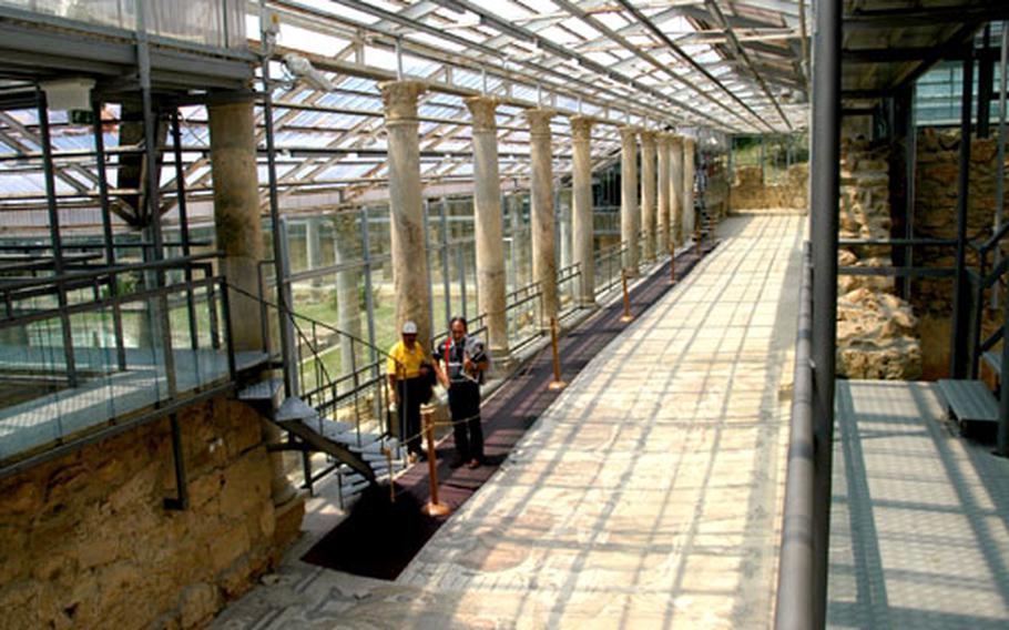 Visitors walk down the large ambulatory at the center of the Villa del Casale, which runs nearly 200 feet.