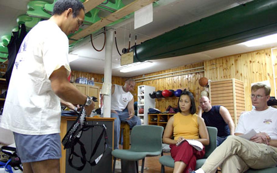 Michael Dong demonstrates one of the sport climbing harnesses to students taking his two-day rock climbing class offered through the Navy Outdoor Recreation Center in Naples.