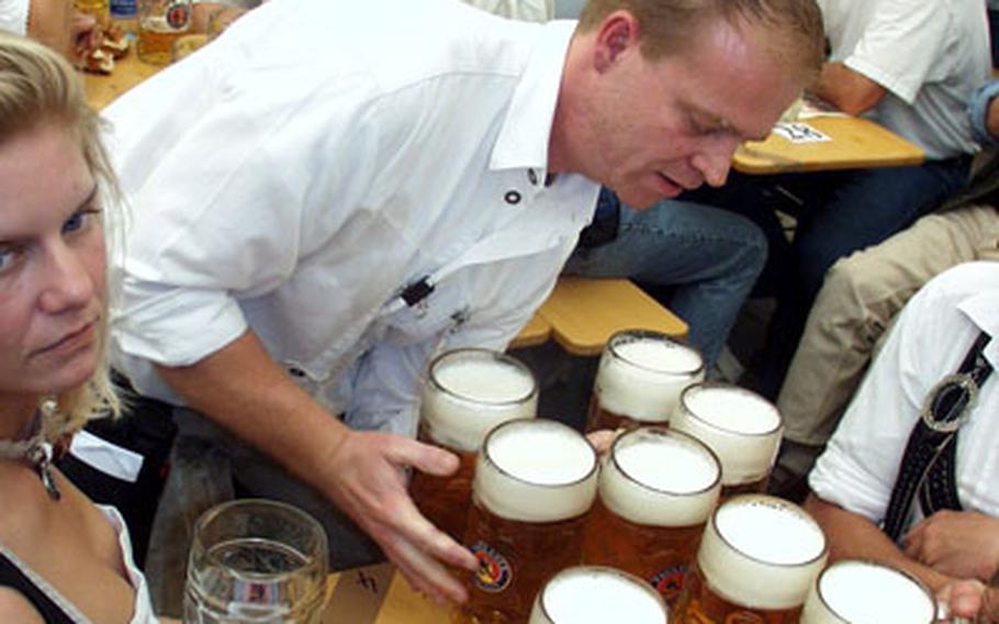 A server delivers a load of Paulaner, which is served in one-liter mugs, to a table of thirsty Oktoberfest partiers.