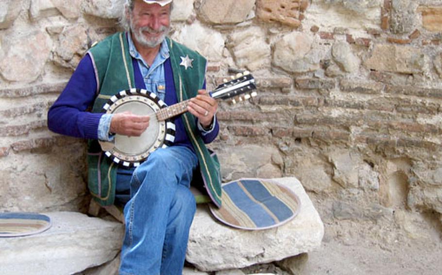 A musician dressed in his version of cowboy attire, complete with sheriff’s badge, plays for donations amid some seaside ruins in Nesebur.