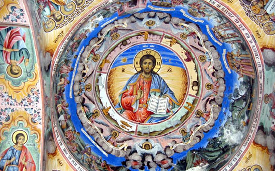 Vividly colored frescoes adorn the walls beneath the porticoes of the Church of the Nativity of the Virgin at Rila Monastery.