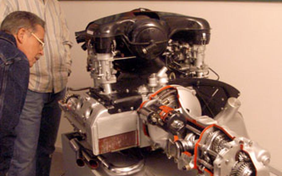 Visitors to the Porsche Museum examine a six-cylinder, air-cooled engine and transmission from a Porsche 911.