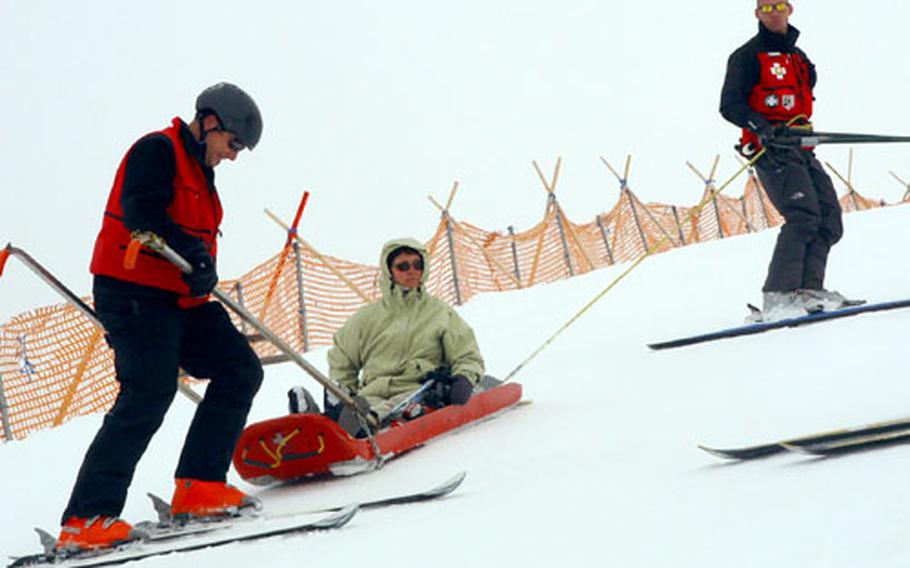 Ski Patrol instructors work on evacuating an injured skier. Here Ben Reed (in the handles) and Brad Pristelski (holding the tail rope) execute a changeover, swapping the tailrope person for the driver of the sled, to allow the driver to rest his legs. They were participating in an instructors&#39; course at Hintertux glacier, Austria.