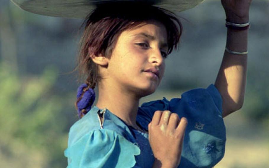 The Hindu Kush montains in northern Afghanistan and nothern Pakistan are barren and rocky, but between the peaks and ridges are lush valleys. People living in the valleys, such as the Swat Valley, still make everyday items such as spice boxes and ornate, if sometimes crude, furnishings. This girl helps her family by running errands, in this case carrying a pan of cheese, in her remote Afghani village just across the border from Pakistan.