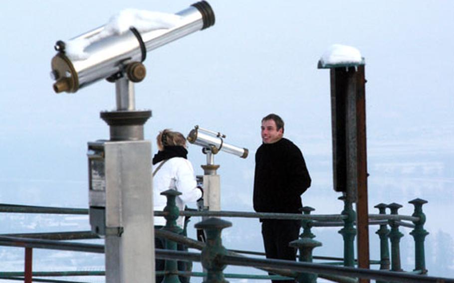A young German couple take souvenir shots of themselves between the telescopes of the Niederwald monument overlooking the Rhine River.