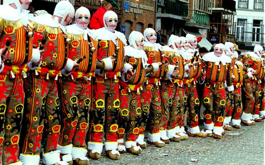 In Binche, Belgium, members of local carnival clubs, the Gilles, display traditional orange costumes and wax masks. These strange masks with mustaches and green glasses, worn by men only, are unique to the Binche festivities.