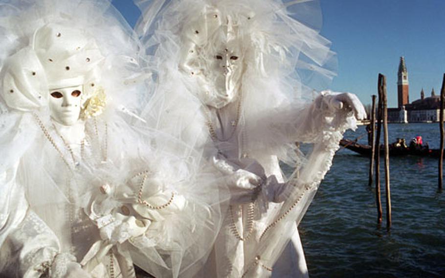 In Venice, the mood is mysterious and elegant. Costumed participants in elaborate and sophisticated costumes pose for photographers during Carnevale celebrations.