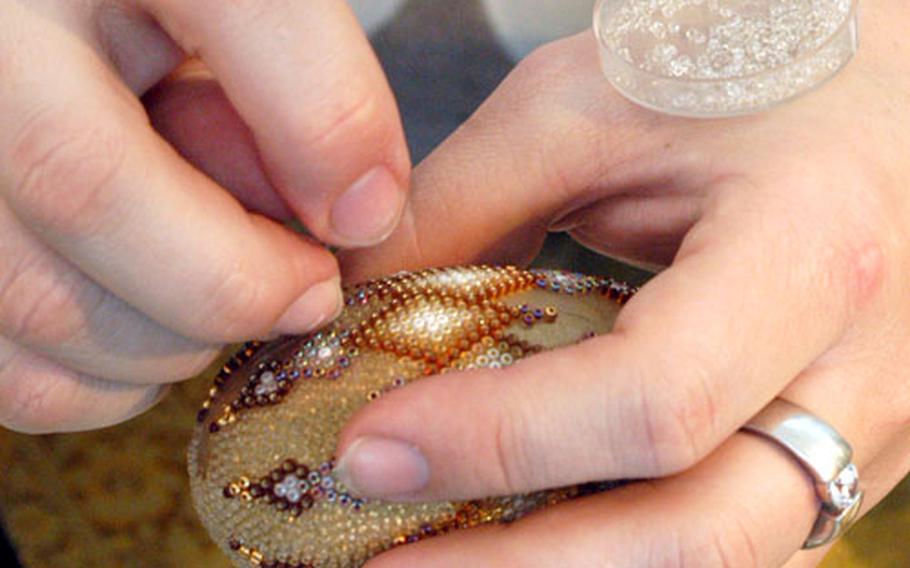 With a steady hand, Helmut Meister glues tiny glass pearls onto an egg.