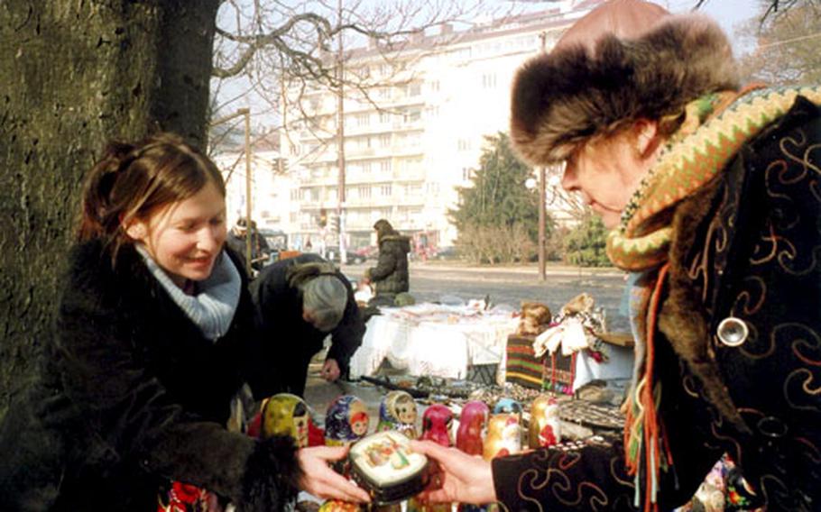 Maria Tracheva, left, shows tourist a Russian lacquered box. She and her husband are both biology teachers, but they also sell Russian souvenirs on the street to make enough money for themselves and their three small children.