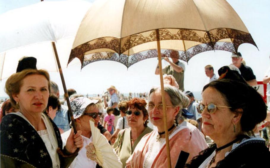 Joining the parade for the festival are the Arlesiennes, women wearing the traditional costume of the area, complete with parasols.