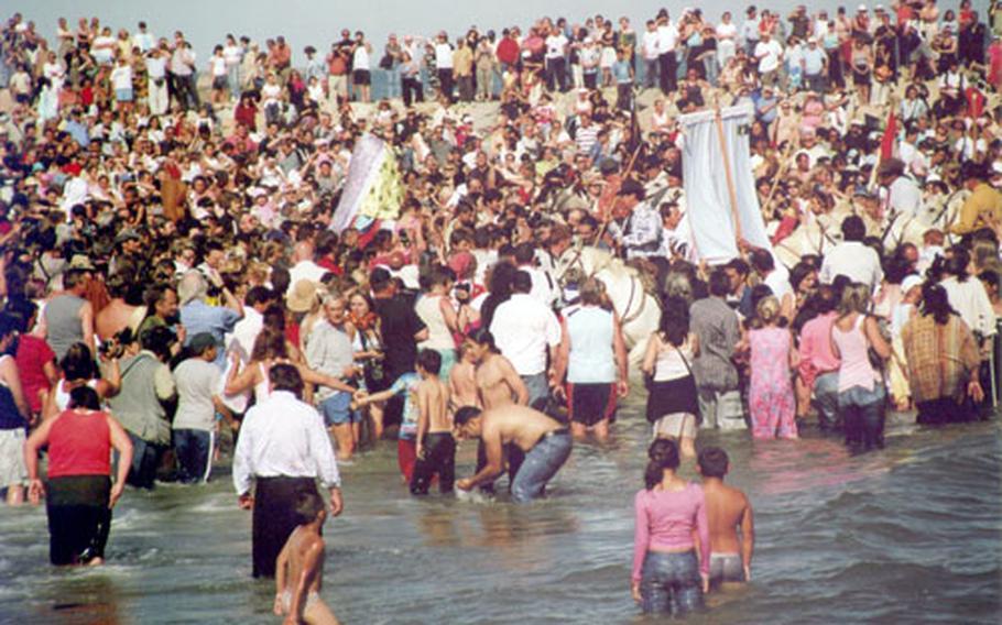 Festival goers gather at the beach and wait for the statue to be paraded into the water.