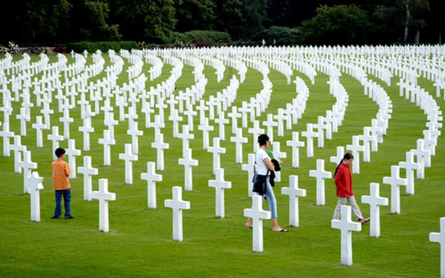 A family walks among the graves of Americans who died fighting in World War II at Henri-Chapelle American Cemetery in Belgium. The crosses and Stars of David mark 7, 992 Americans who are buried here.