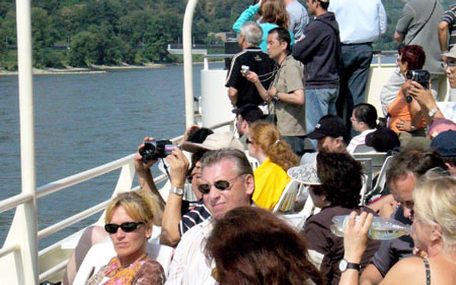 A group of modern-day castle “invaders” — tourists on a cruise of the Rhine River — relax within easy view of castles and castle ruins along the river.