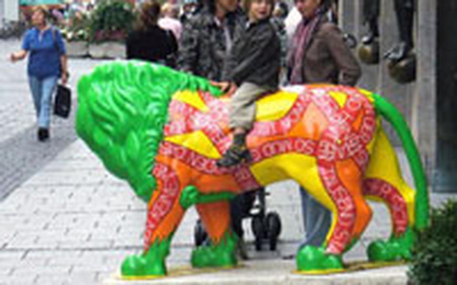 A child is happily distracted on the colorful Hugendubel-sponsored lion while his mother chats with a friend.