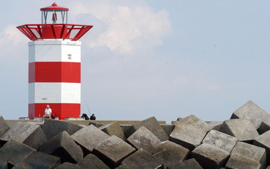 A lighthouse marks the entrance to the port at Scheveningen, Netherlands. Until about 200 years ago, Scheveningen was a small fishing village. Now it is the most popular seaside resort in Holland.