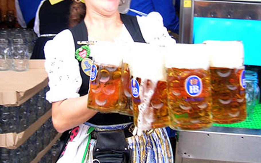 A waitress rushes several one-liter mugs of beer from the serving area to eager patrons on the opening day of the this year’s Oktoberfest.