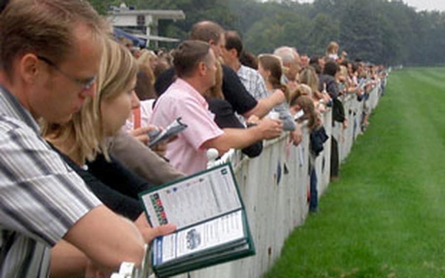 Patrons gather along the rail as they wait for another race to begin at the Galopprennbahn Frankfurt.