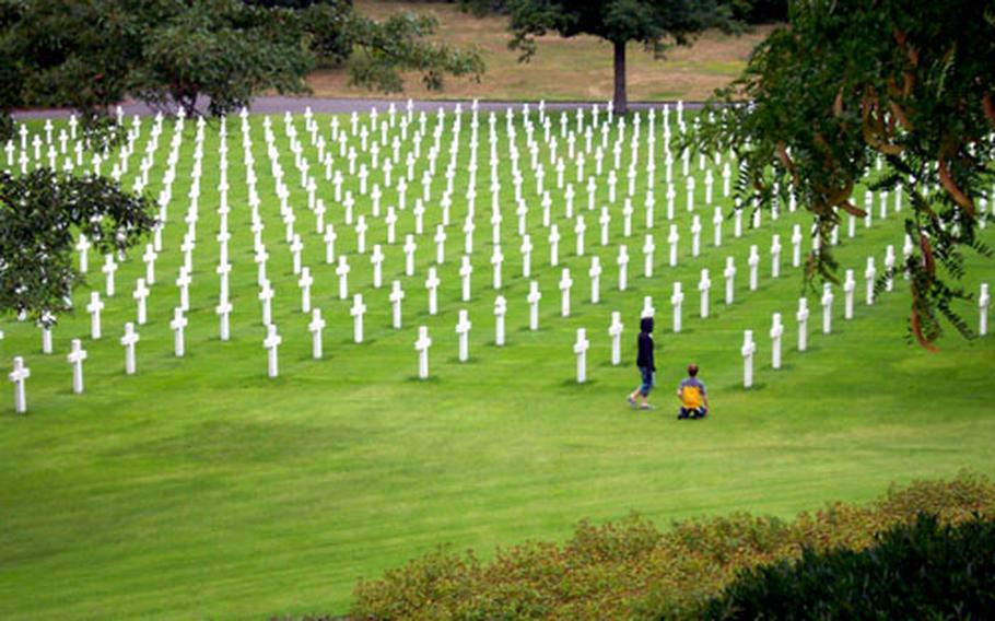 Visitors look at the rows of military graves, perfectly aligned in every direction. Originally about 16,000 troops were buried at Lorraine American Cemetery, but many were later returned to the United States for burial.