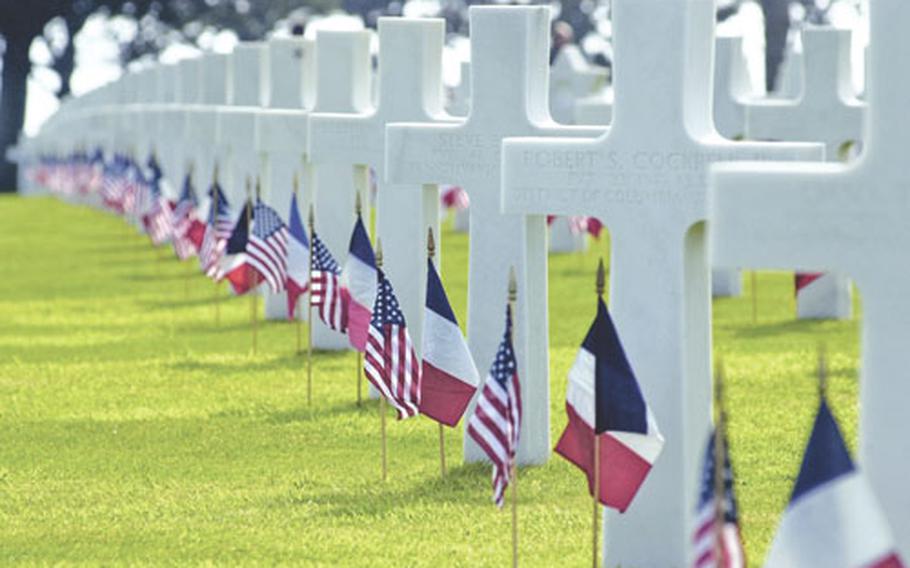 A row of crosses decorated with American and French flags for Memorial Day at Normandy American Cemetery. The cemetery, where 9,387 American war dead are buried, is on a cliff overlooking the D-Day landing sites at Omaha Beach.