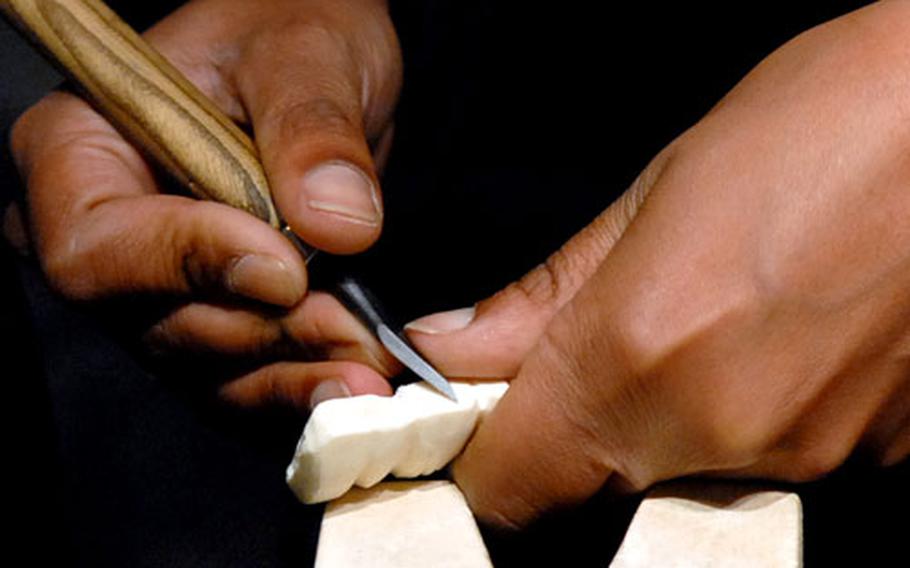 With a skilled hand, a carver demonstrates how ivory is shaped. She said that with ivory, it is more a matter of scraping the surface than the whittling that one does with wood.