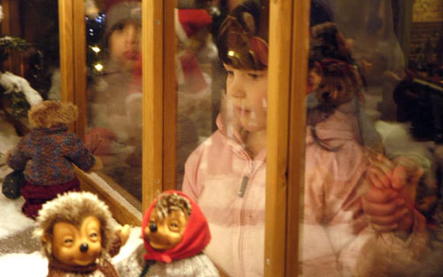 A young girl looks at a Christmas scene with "Mecki" the hedgehog dolls at the Christmas market in Basel, Switzerland.