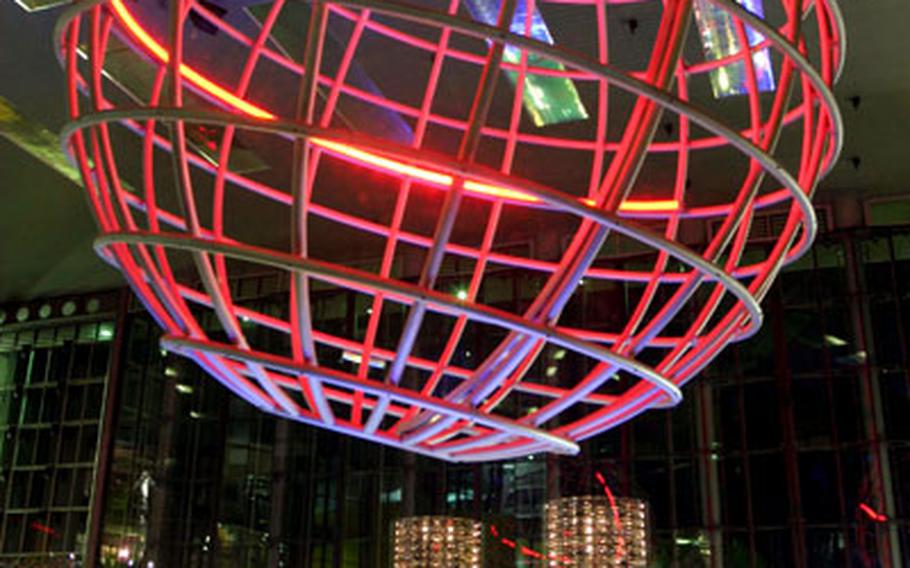The reception room in the Konzern- Forum, or Group Forum, includes a glass- enclosed piazza where a 4½-ton globe is suspended over a glass floor under which there are 70 small rotating globes dedicated to different subjects. At night, walking under the mammoth globe with the smaller globes glittering under your feet is magical.