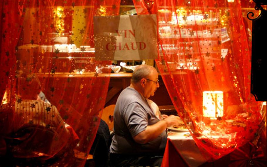 An Alsatian local enjoys dinner in one of the decorated downtown restaurants in Sélestat. The sign indicates that hot wine is served.