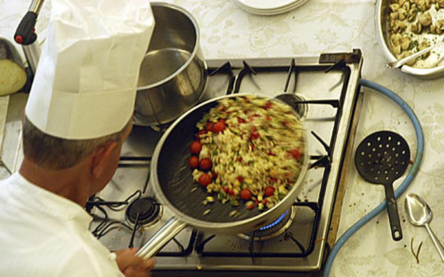 Chef Bruno Pederzolli stirs the ingredients for a dish by flipping them in the pan. Students at the Gourmet Italia cooking class could watch all the chef's moves through a mirror angled on the wall above him.