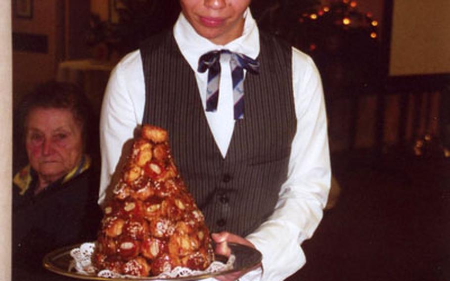 A student at the École de Paris des Métiers de la Table du Tourisme et de L’Hôtellerie proudly presents an elaborate dessert creation, a tower of cream puffs. The waitress cut off part of the pyramid for each serving.