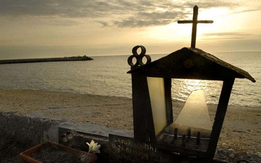 An early morning sunrise is seen through a small memorial in Romania’s treasured coastal town of Mangalia. Romania is 87% Christian Orthodox.