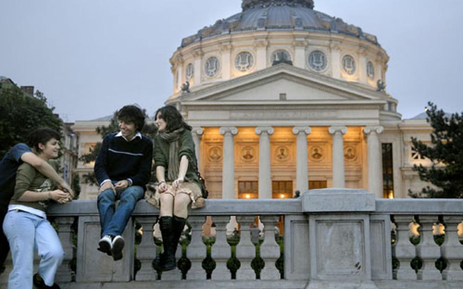 Young Romanians sit in front of the Atheneum, Bucharest&#39;s most prestigious concert hall, located in the Revolution Square.