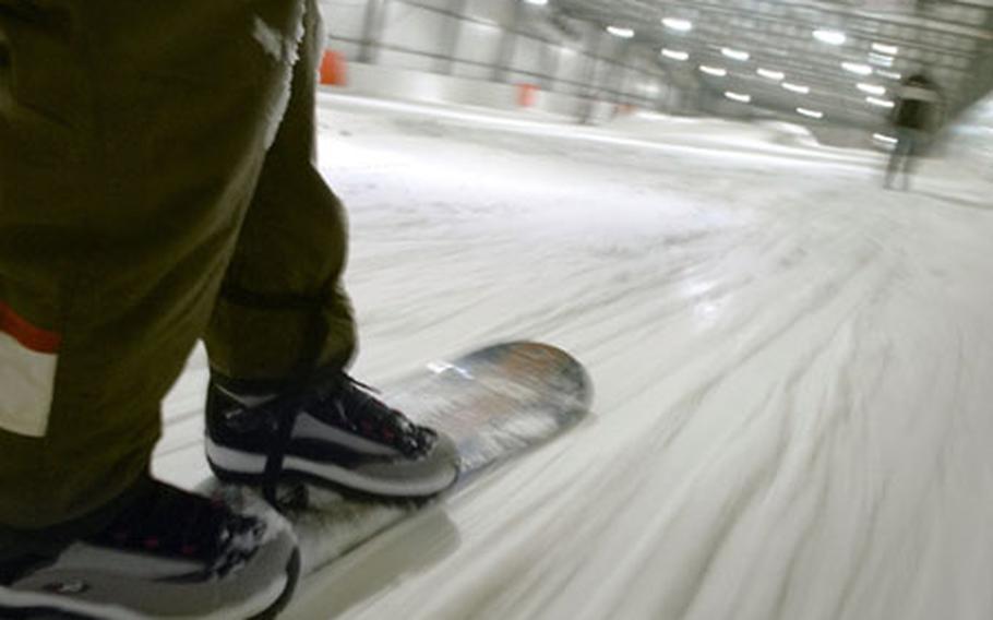 A snowboarder cruises up the poma lift at the Snowhall, Europe’s longest indoor ski run June 6, 2007, in Amnéville, France.