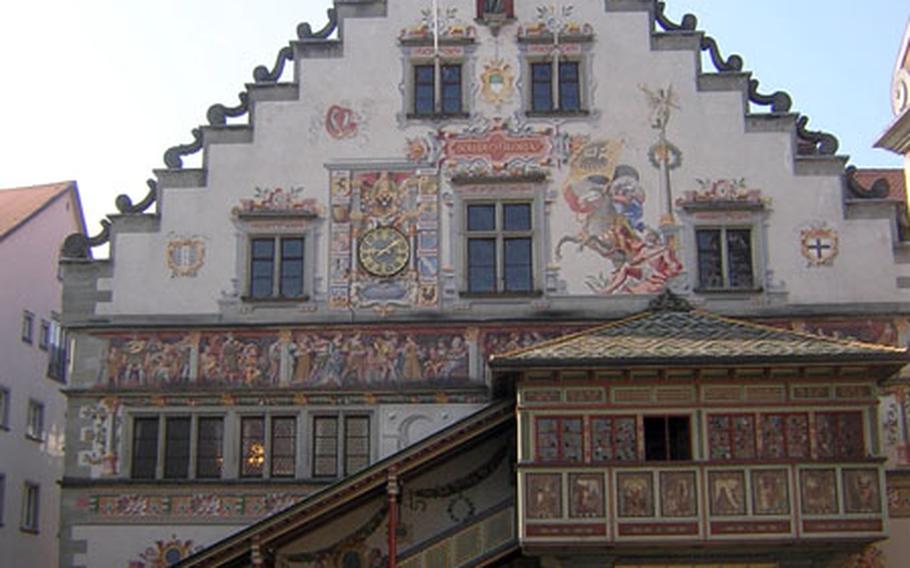 The painted front of the old town hall includes scenes from the Bible and local history. The wooden steps and porch on the front were rebuilt after a fire from the original plans. The painted clock face is to the left of the center window.