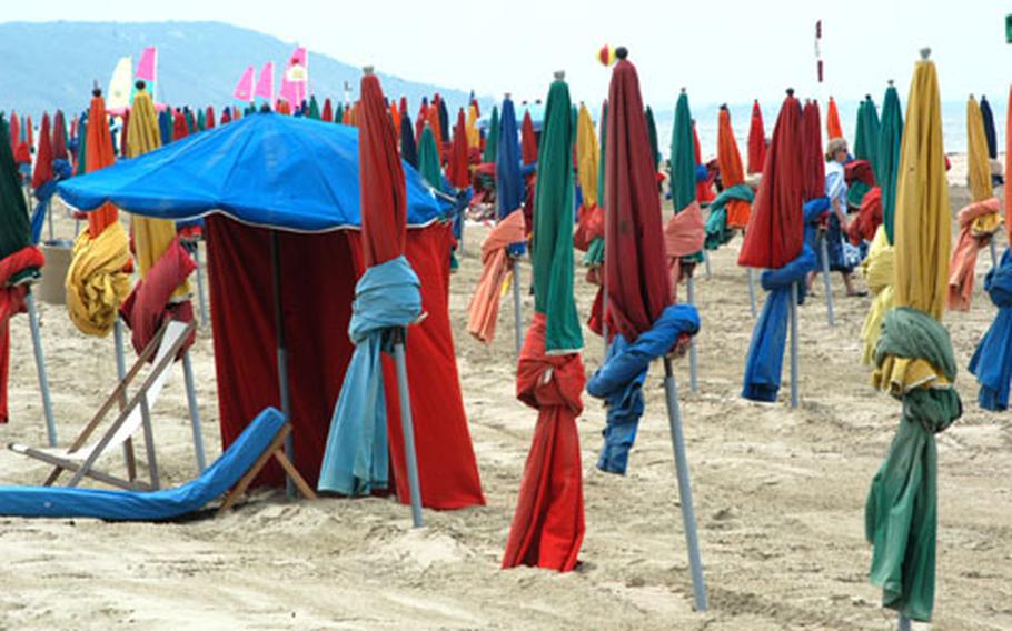 An early sunbather is hidden in a forest of colorful umbrellas gracing the main beach of Deauville, France.