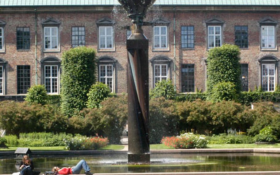 Two women take a break under the fountain in the Royal Library Gardens at the Slotsholmen complex in Copenhagen.