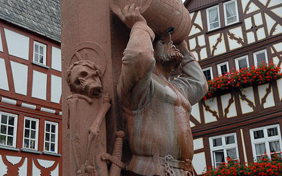 This 1985 statue of wine-drinking, knight-turned- city manager Friedrich von Hattstein is part of a fountain in a Limburg square. In the background are two of the town&#39;s many half-timbered houses.