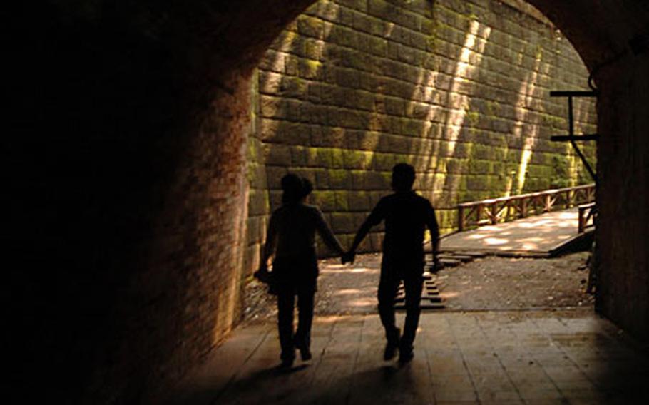 A Japanese couple holds hands as they visit the many historical remains on Monkey Island.