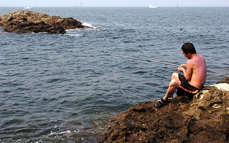 A Japanese man fishes off the reef of Monkey Island.