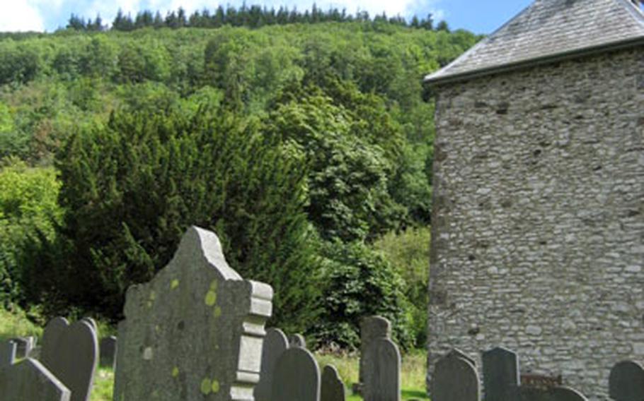 Blue skies over the Berwyn Mountains of Wales form the backdrop for the tower and gravestones at the Church of St. Melangell.