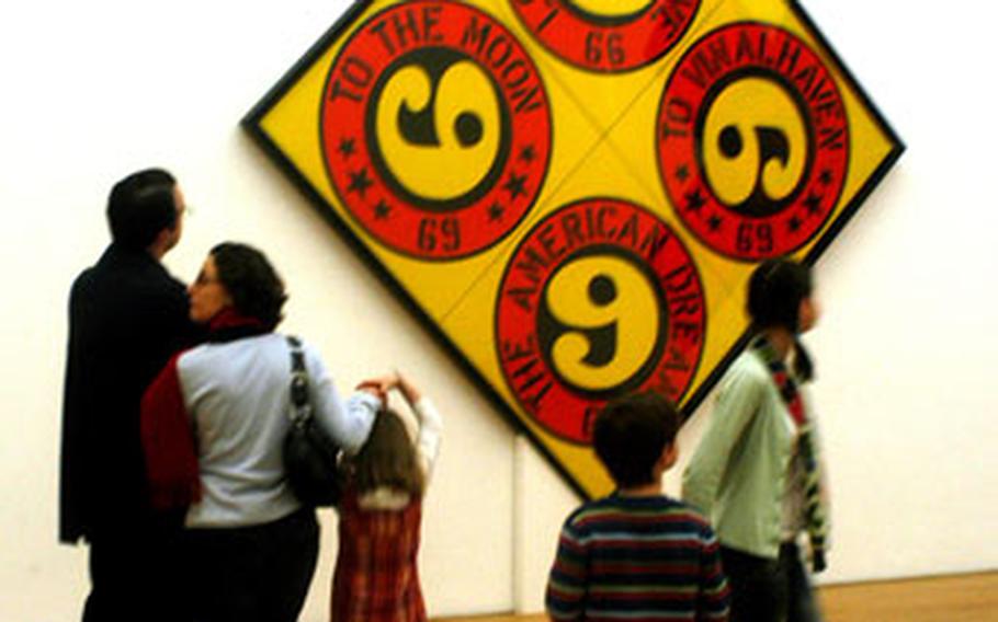 At the Museum Wiesbaden, an American family enjoys the 2002 painting by Robert Indiana called “The 6666, The American Dream.” The museum is honoring Indiana with a special exhibit titled “Robert Indiana, Painter of Signs.”