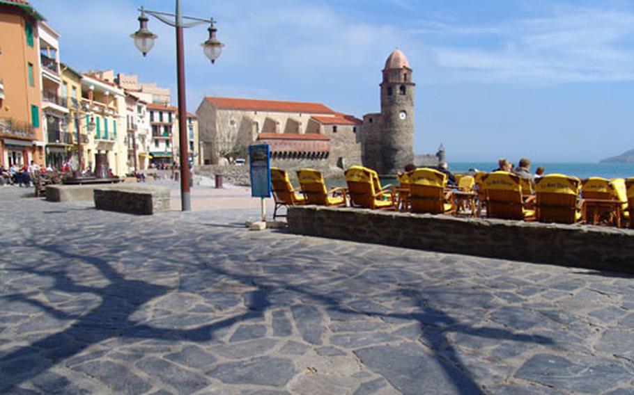 Off-season visitors enjoy the sun on terraces fronting one of the four beaches in the ancient Catalan fishing village of Collioure.