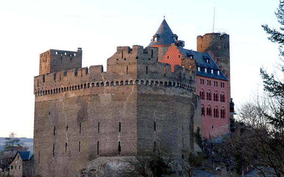 A setting sun casts warm light on Schönburg castle, which sits above the Rhine River town of Oberwesel, Germany. Paths from town lead up to the castle.