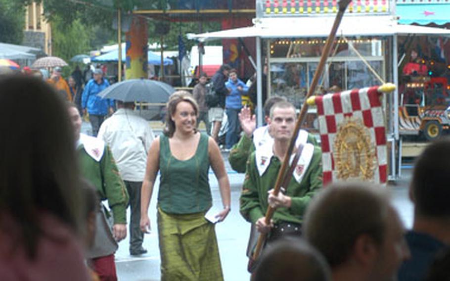 The new wine queen is escorted into the festival tent by a man hoisting the flag of the wine guild.