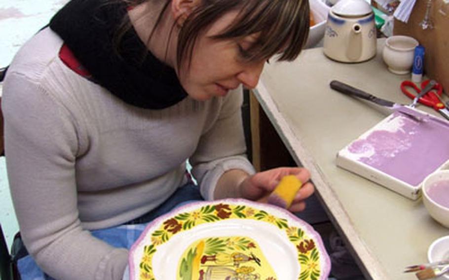 A worker at the Faïence Manufacturer of Lunéville-Saint Clement paints finishing touches on a plate. All of the factory’s products are made by hand.