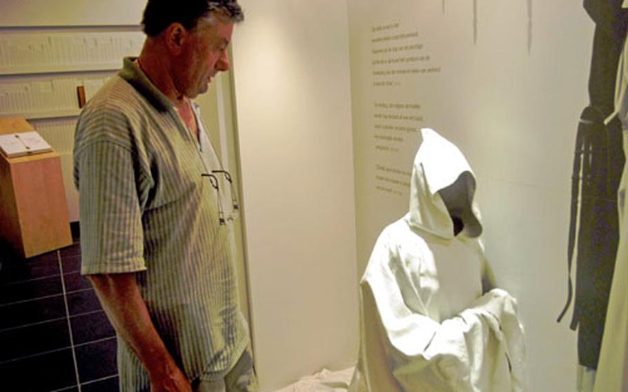 Mark Bode, a spokesman for the abbey, looks at a display showing the cloak worn by the monks during services. The display is part of a museum located in a small cafe across from the abbey.
