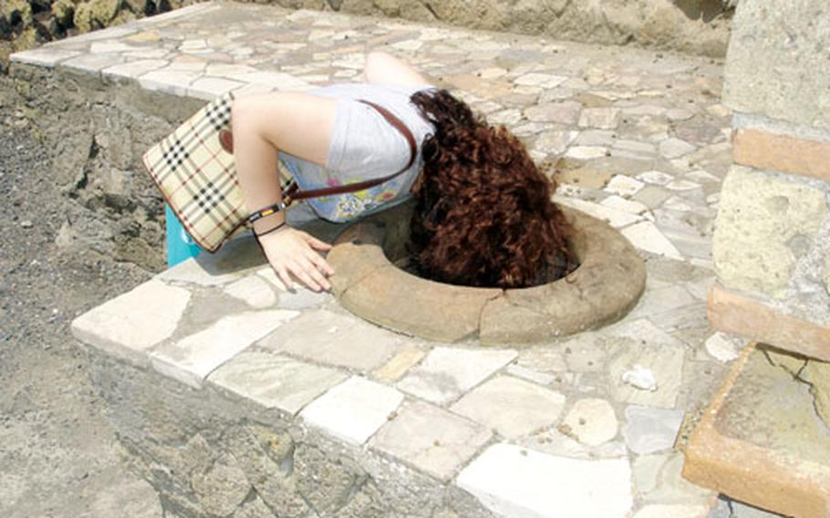 Curiosity gets the better of one young visitor exploring the thermopolium, an ancient outdoor restaurant of sorts, where cooked food or mulled wine was served from large earthenware jars set into stone counters.