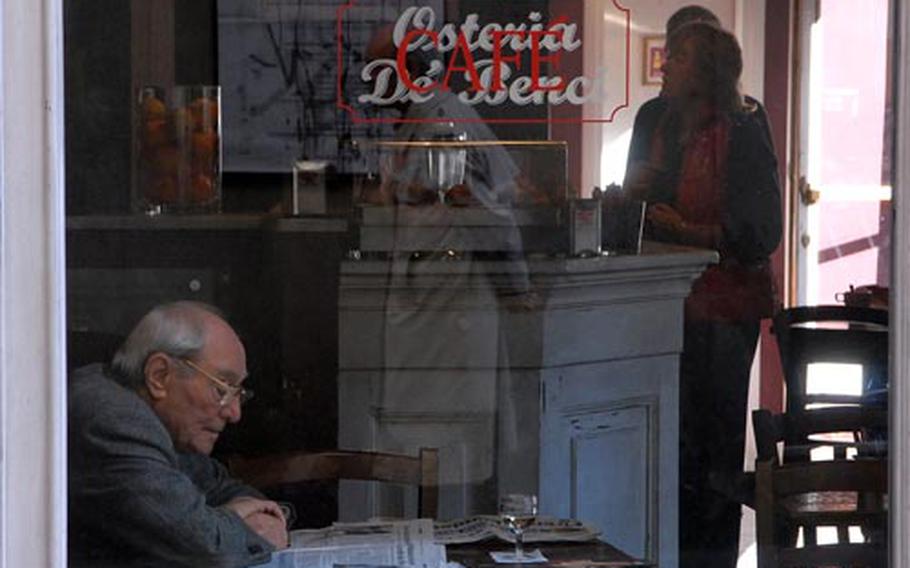 An elderly gentleman enjoys a glass of wine and the morning paper in a Florence, Italy, cafe.